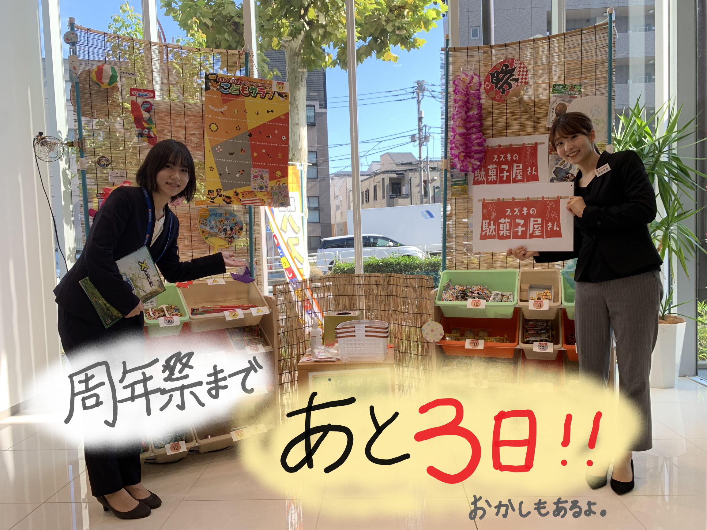 駄菓子屋さんの前に立つスタッフ２名